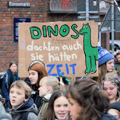 Fridays for Future - Demo in Hamburg - 01.03.2019 . DemonstrantInnen auf dem Gänsemarkt tragen ein  Demoschild mit dem Slogan: Dinos dachten auch sie hätten Zeit.