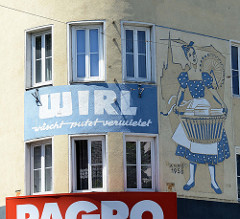 Wohnhaus, Geschäftshaus in Wien - rundes Eckhaus, errichtet 1958. Fassadenmalerei Waschfrau mit Wäschekorb - WIRL, wäscht - putz - vermietet.