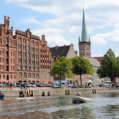 Promenade und Anleger an der Trave in Lübeck; historische Gebäude / Speicher der Lübecker Altestadt - Kirchturm der Petrikirche.