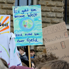 Fridays for Future - Demo in Hamburg - 01.03.2019. Protestschild bei der Abschlusskundgebung auf dem Hamburger Rathausmarkt: Es geht um unsere Welt und nicht um euer Geld.