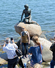 Touristen fotografieren sich und die Kleinen Meerjungfrau an der Uferpromenade Langelinie in Kopenhagen. Bronzefigur nach dem Vorbild in dem gleichnamigen Märchen des dänischen Dichters Hans Christian Andersen; Bildhauer Bildhauer Edvard Eriksen, 191