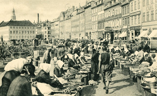 Historische Ansicht vom Fischmarkt in Kopenhagen - Frauen in Tracht verkaufen frische Fische aus Körben und Kisten - am Kanalufer liegen Fischerboote.