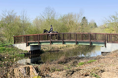 Holzbrücke über die Bille - eine Reiterin überquert den Hamburger Fluss bei Billwerder.