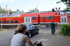 Fotos aus dem Hamburger Stadtteil Tonndorf - Bezirk Hamburg Wandsbek;  Bahnübergang an der Jenfelder Straße - die Schranke ist geschlossen ein Zug rast vorbei.