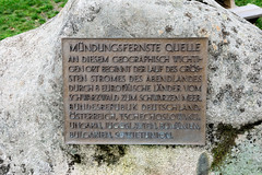 Quelle der Breg in Furtwangen - Schwarzwald in Baden-Württemberg; Hauptquellfluss der Donau, hydrologische Donauquelle. Metalltafel an einem Findling mit der Aufschrift: Mündungsfernste Quelle; an diesem geographisch wichtigen Ort beginnt der der Lau