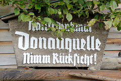 Quelle der Breg in Furtwangen - Schwarzwald in Baden-Württemberg; Hauptquellfluss der Donau, hydrologische Donauquelle. Geschnitztes Holzschild mit der Inschrift Naturdenkmal Donauquelle, nimm Rücksicht!