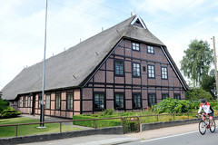 Neuengamme  ist ein Hamburger Stadtteil im Elbmarsch-Gebiet der Vierlande im Bezirk Bergedorf. Hofanlage, restauriertes Fachwerkgebäude mit Reetdach im Neuengammer Hausdeich, Rennradfahrer.