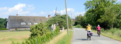 Fotos aus dem Hamburger Stadtteil Reitbrook, Bezirk Bergedorf. Reedachgebäude / Wohnwirtschafthaus, im Hintergrund die Reitbrooker Mühle - Radfahrerinnen.