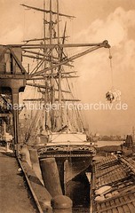 Historische Hafenszene Hamburg Altona - Frachtsegler Olaf Kyrre mit dem norwegischen Heimathafen Langesund. Am Haken des Hafenkrans hängt eine Ladung Säcke; im Vordergrund ein Lastkahn.