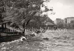 Windiges Wetter an der Aussenalster, Wellen schlagen an das Alsterufer - im Hintergrund Gebäude am Alsterglacis.