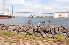 Fotos der Köhlbrandbrücke im Hamburger Hafen - Verbindung zwischen den Stadtteilen Steinwerder und Wilhelmsburg. Rostiges Fahrrad am Ufer des Köhlbrands - im Hintergrund die Brücke.