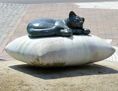 Teterow  ist eine Stadt im Landkreis Rostock in Mecklenburg-Vorpommern; Kunst im öffentlichen Raum - Katze / Bronze liegt auf einem Stein-Kissen.