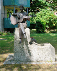 Fotos aus dem Hamburger Bezirk und Stadtteil Wandbek; Bronzeskulptur Gitarre spielendes Mädchen in der Grünanlage am Quarree.