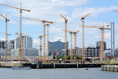 Fotografien aus dem Hamburger Stadtteil Hafencity, Bezirk Hamburg Mitte; Baukräne auf der Baustelle vom Überseequartier, rechts fährt ein Sportboot in den Magdeburger Hafen ein.