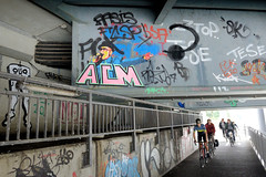 Fotos aus dem Hamburger Stadtteil Rothenburgsort, Bezirk Hamburg Mitte; Fahrradunterführung unter der Billhorner Brückenstraße entlang des Oberhafenkanals - Graffiti am Brückenträger, Fahrradfahr in Fahrt.