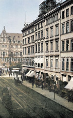 Etagenhäuser und Geschäfte mit Markisen in der Hermannstraße - Hamburger Altstadt - Pferdefuhrwerke auf der Straße, im Hintergrund das Hamburger Rathaus, ca. 1900.