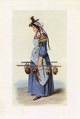 Milchmädchen in Frankreich - die in einer Tracht gekleidete Frau trägt die Milchkrüge an zwei Stangen.