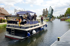 Banzkow ist eine Gemeinde im Landkreis Ludwigslust-Parchim in Mecklenburg-Vorpommern; ein Motorboot legt vom Warteplatz ab + fährt Richtung Brückendurchfahrt.