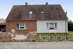 Breese ist ein Ort und gleichnamige Gemeinde im Landkreis Prignitz in Brandenburg; Doppelhaus mit unterschiedlicher Fassadengestaltung - Gartenzaun.