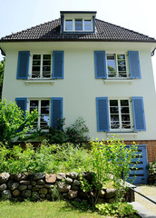 Fotos aus dem Hamburger Stadtteil Bergedorf; Wohnhaus mit blauen Fensterlägen / Feldstein-Gartenmauer.