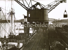 Kohleverladung am Holthusenkai auf dem Hamburger Kleinen Grasbrook - Frachter am Kai - Kran und Güterwaggons mit Kohle beladen. Im Hintergrund der Verteilungszentrum und die Elbbrücken.